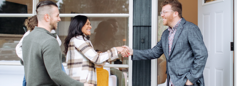 A couple with a child smiles while they shake hands, meeting a REALTOR®